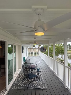 A covered porch with a ceiling fan, a table with chairs, and a view of a lake. - Enjoy waterfront home on Charlotte Harbor. Available Winter '26/Spring '27 (Punta Gorda)