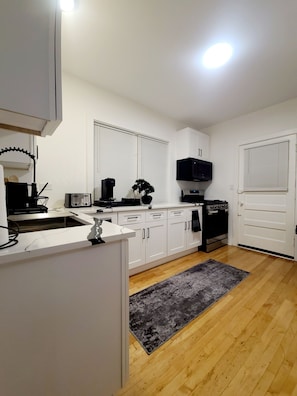 A modern kitchen with white cabinets, a built-in oven, a microwave, and a sink. - A 3-bedroom, 2-bathroom residence that provides ample space and comfort. (Chicago)