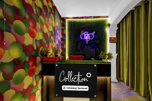 A reception area with a colorful wall, a neon sign, and a green curtain.