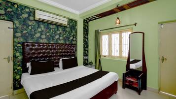 A bedroom with a large bed, a wardrobe, a mirror, and an air conditioning unit.