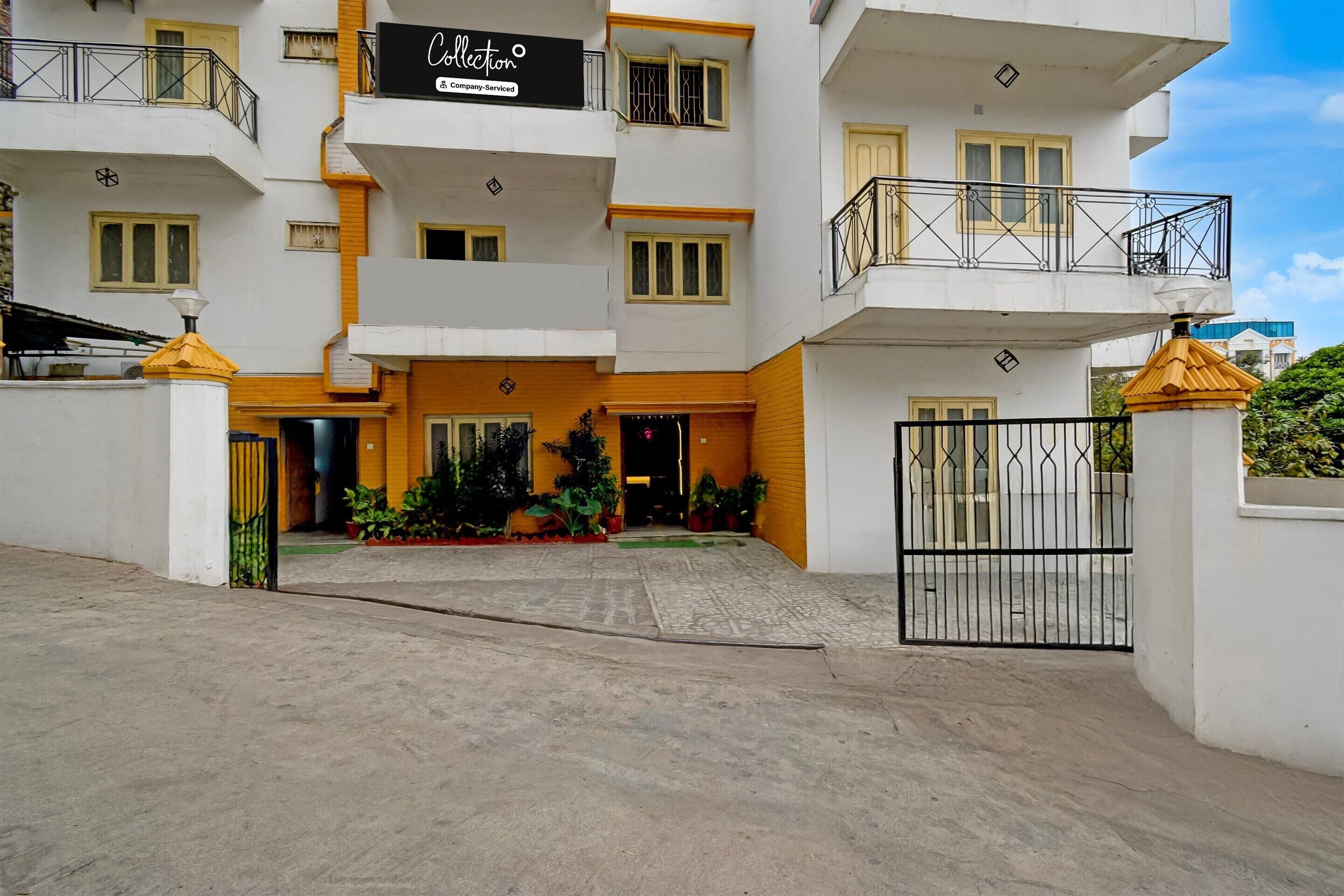 A multi-story building with a gated entrance, balconies, and potted plants.