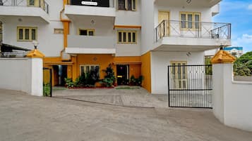 A multi-story building with a gated entrance, balconies, and potted plants.