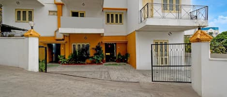 A multi-story building with a gated entrance, balconies, and potted plants.