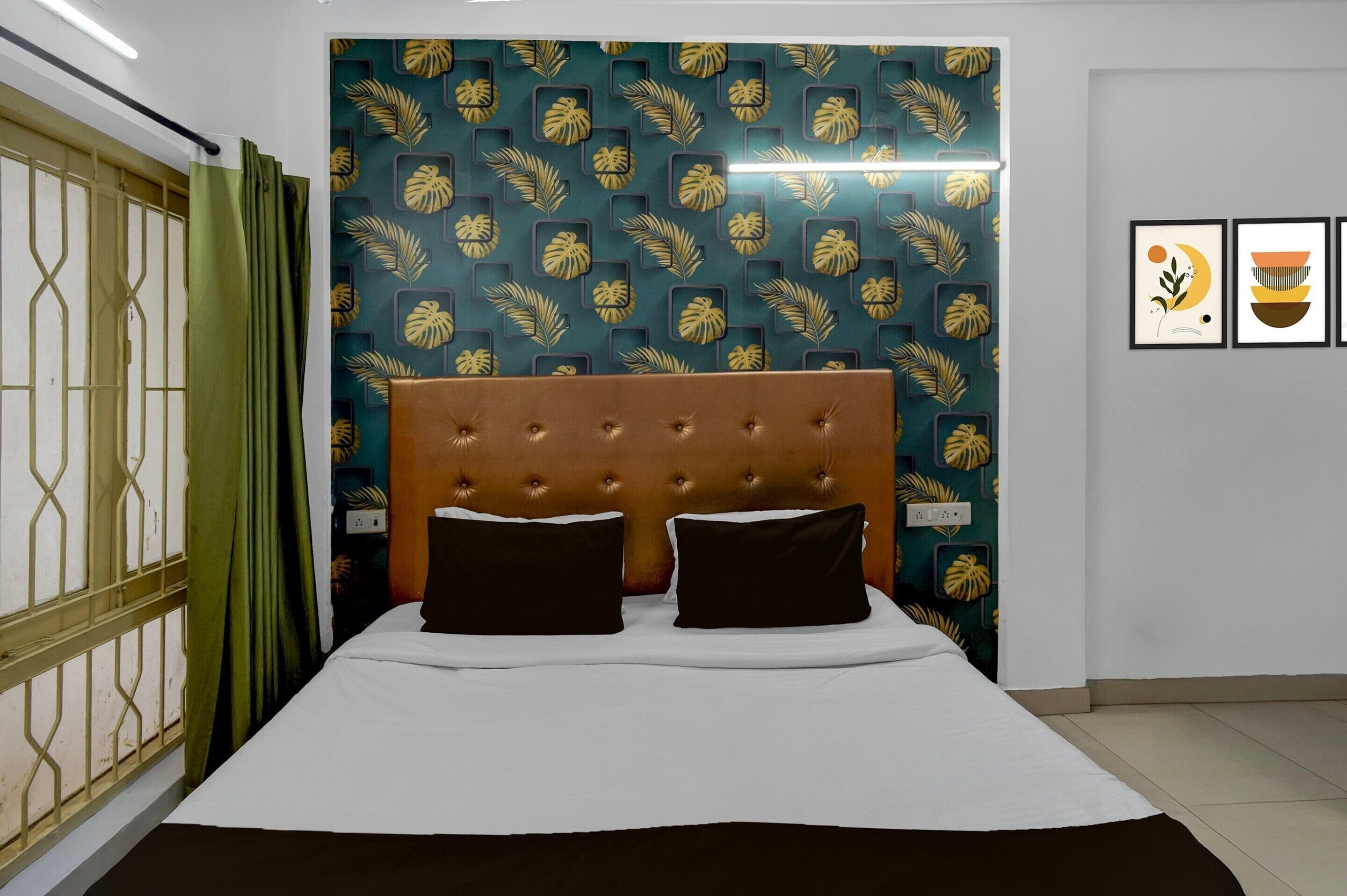 A bed with a tufted headboard, a green curtain, and a patterned wallpaper.