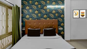 A bed with a tufted headboard, a green curtain, and a patterned wallpaper.