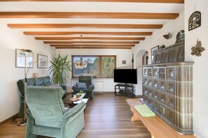 A living room with a sofa, armchair, TV, and a cabinet.