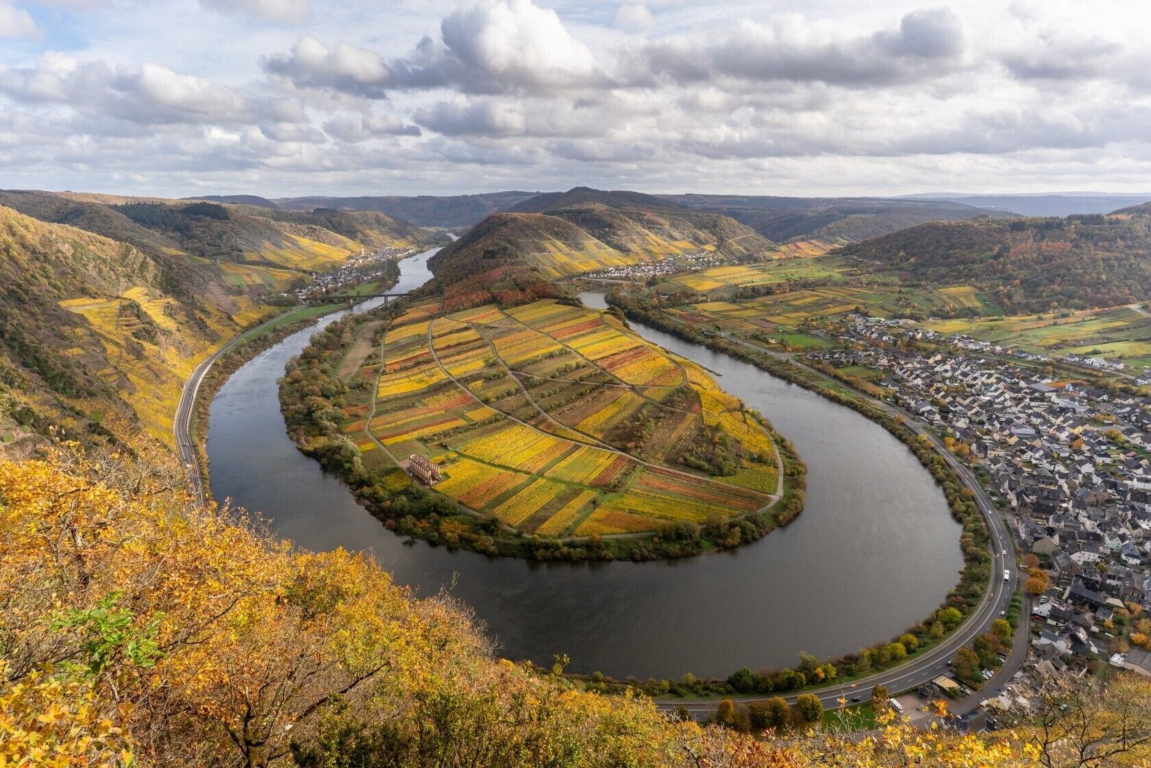 Ein Fluss schlängelt sich durch ein Tal mit Feldern und einer kleinen Stadt.