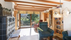 A living room with a sofa, a chair, a bookshelf, and a large window.