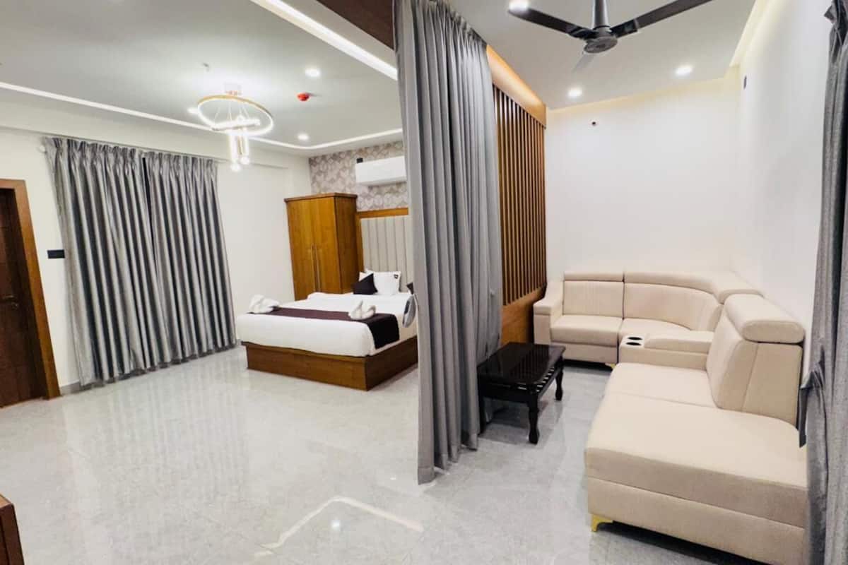 Une chambre d’hôtel moderne équipée d’un lit, d’un canapé, d’une petite table et d’une armoire.