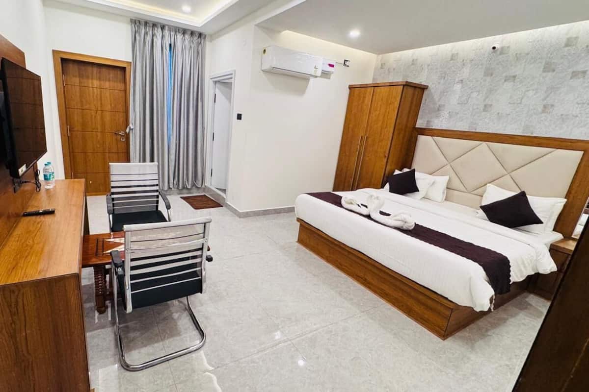 Une chambre d’hôtel comprenant un lit, un bureau avec une chaise, une télévision et une armoire.