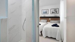 Een hotelkamer met twee bedden, een houten hoofdeinde en twee ingelijste foto's aan de muur.