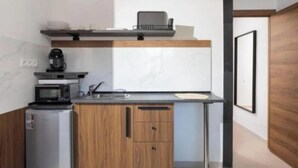 Een kleine keuken met een magnetron, koffiezetapparaat en een spoelbak.