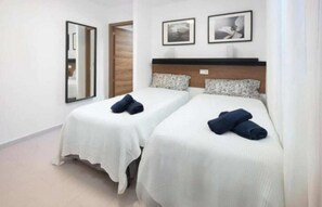 A hotel room with two beds, white bedding, a wooden headboard, and two framed pictures on the wall. - Apartment 3 Almayate Beach (Almayate Bajo)