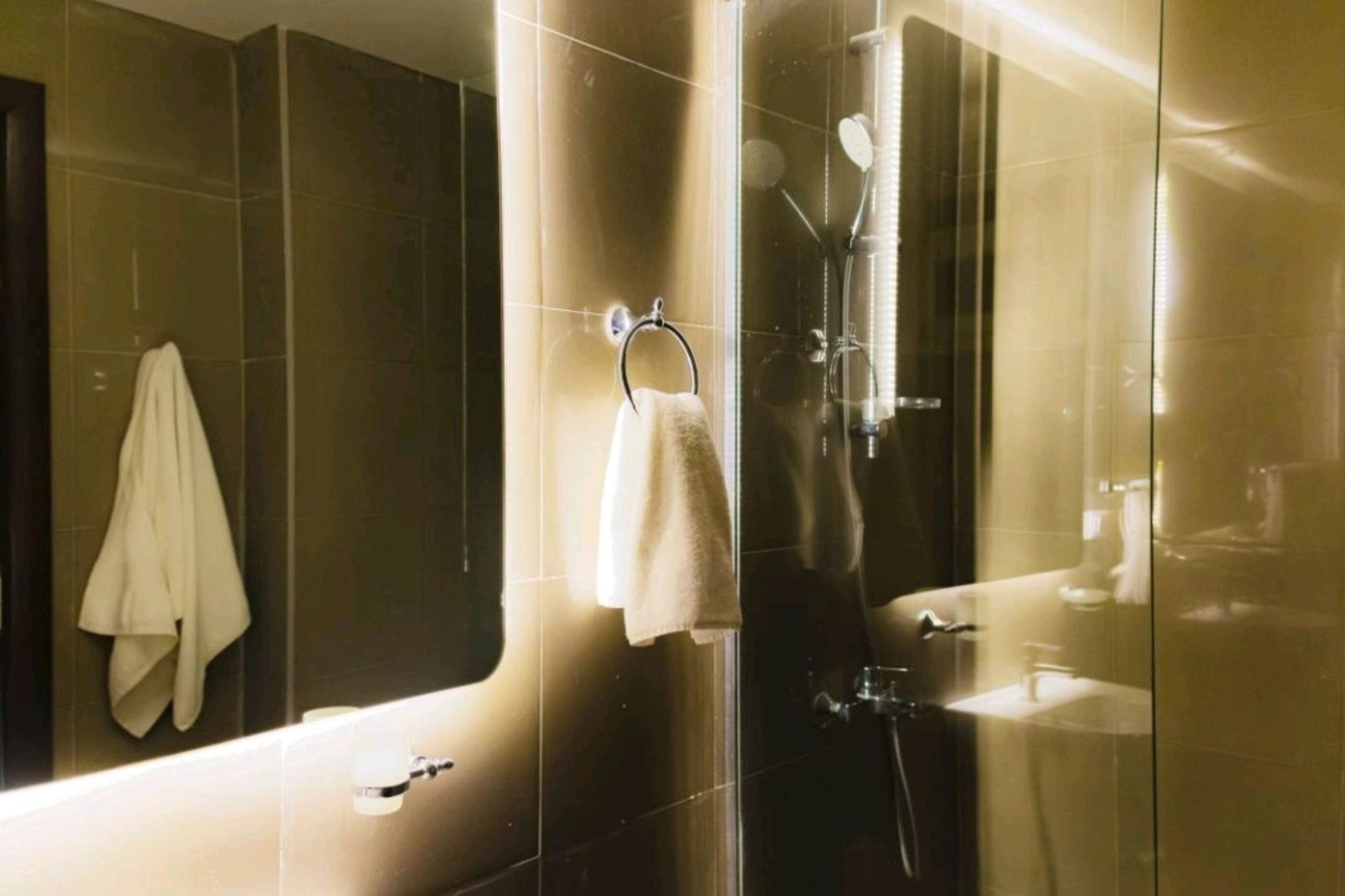 A modern bathroom with a glass-enclosed shower, a visible sink, and a towel rack.