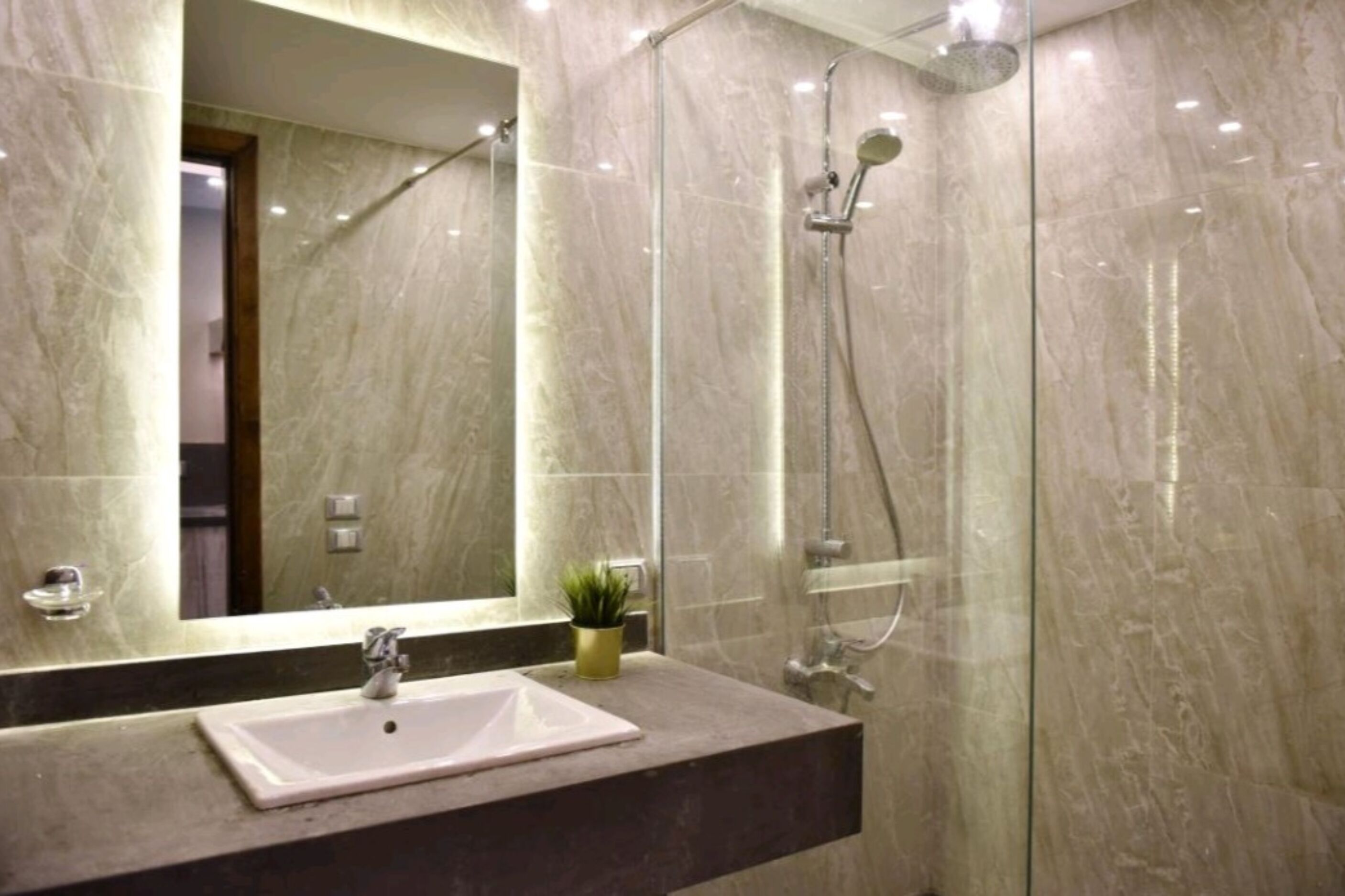 A modern bathroom with a marble sink, a glass shower enclosure, and a mirror reflecting the interior.