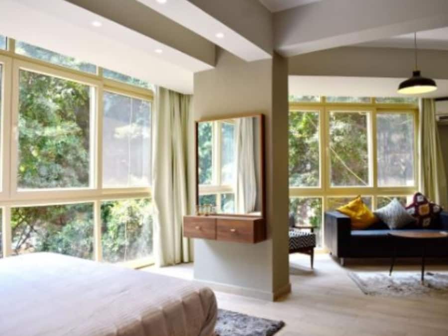 Un dormitorio con una ventana grande, una cama, una mesita de noche y un sofá.