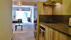 Een moderne keuken met een inbouwfornuis, oven en magnetron. In de achtergrond is een eethoek met een tafel en stoelen te zien.