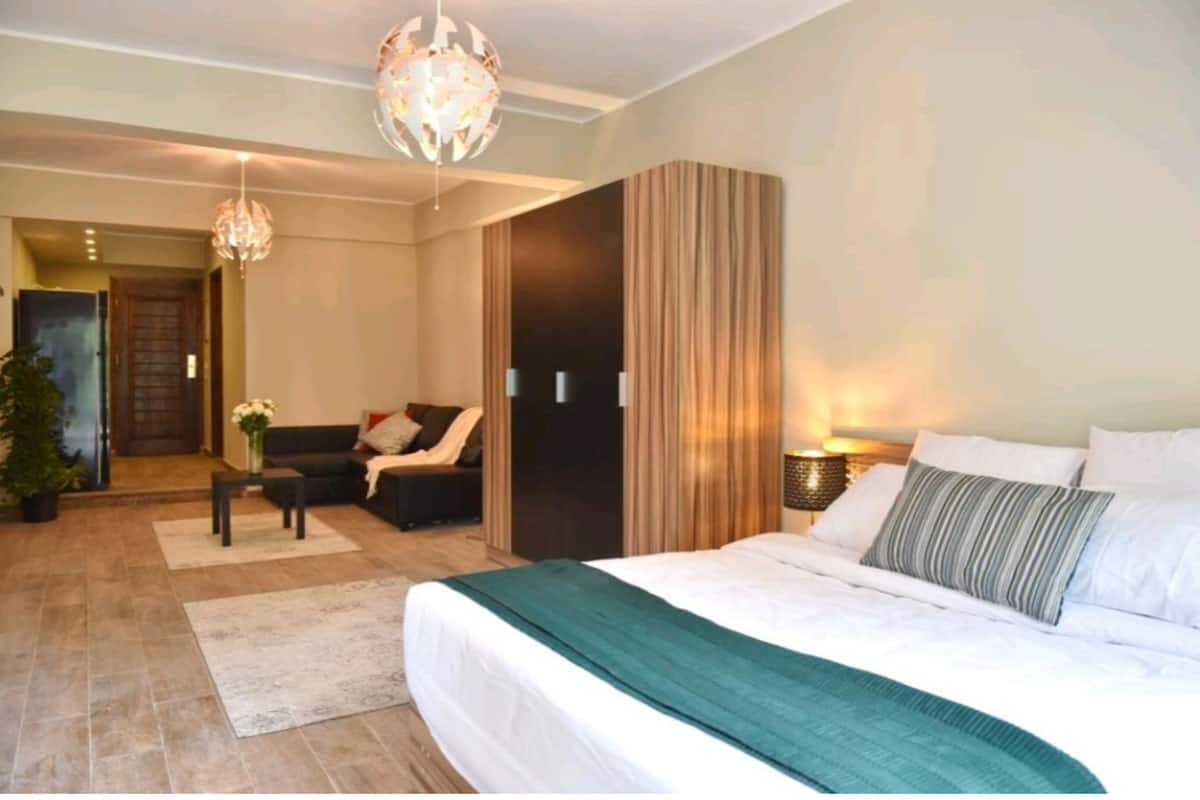 Una habitación de hotel con una cama grande, un sofá, una mesita y un candelabro.
