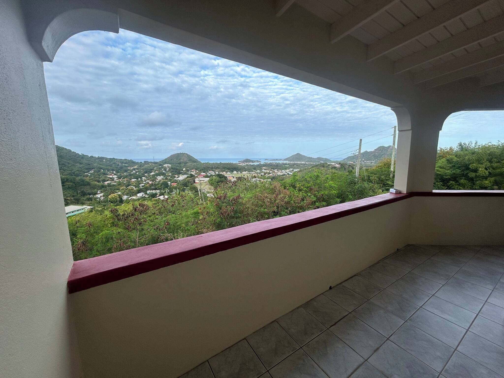 A balcony with a view of a town and hills.