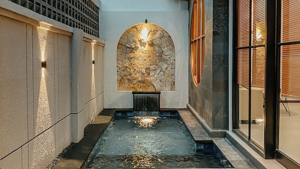 Ein Innenhof mit Holzterrasse, steinernen Bögen und einem Wasserspiel.