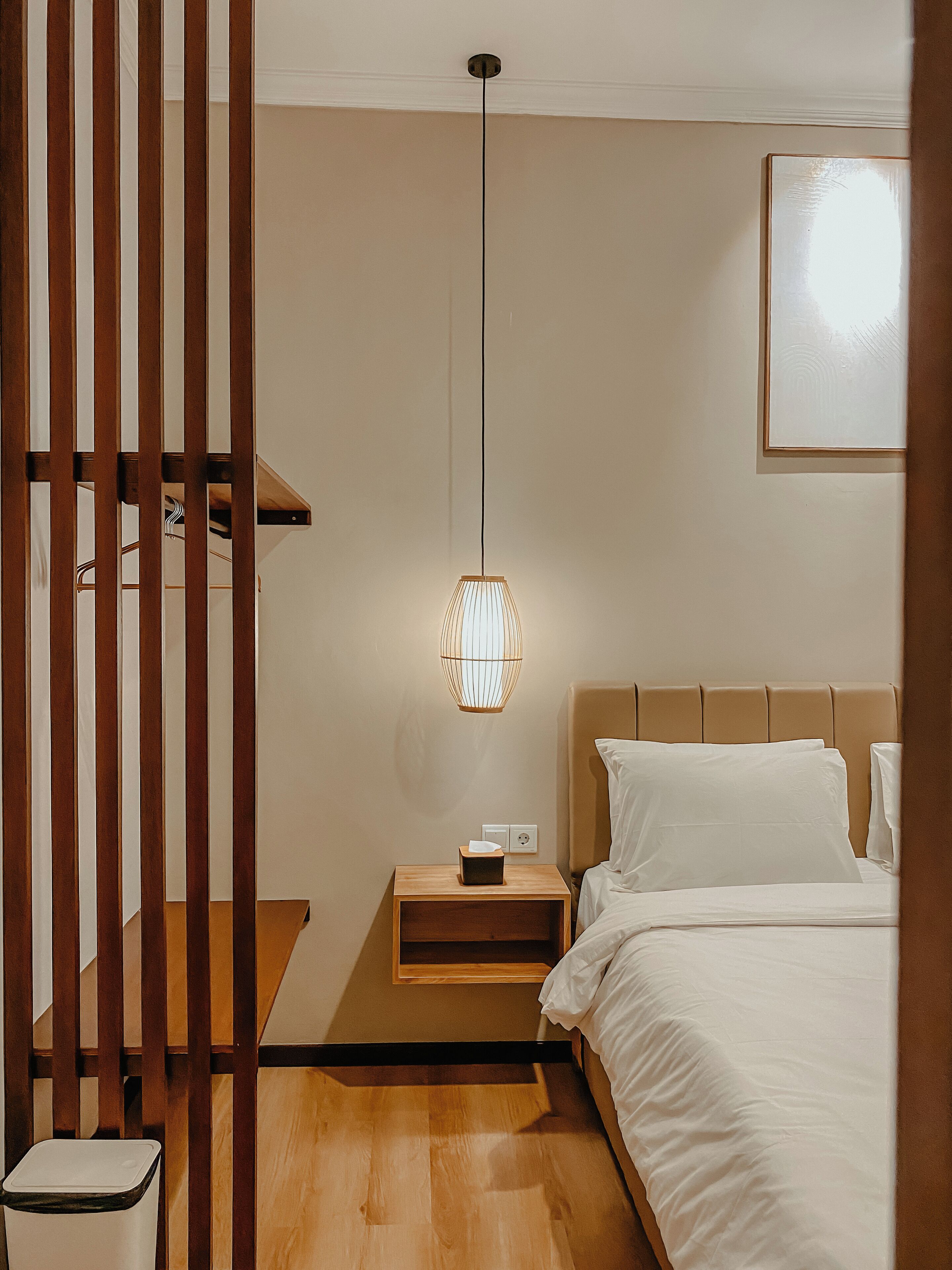 Une chambre à coucher comprenant un lit, une table de chevet, une commode et un luminaire suspendu.