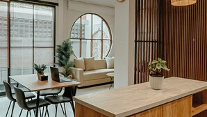 Eine moderne Küche mit einer Holzinsel, Pendelleuchten und einem großen Fenster mit Jalousien.
