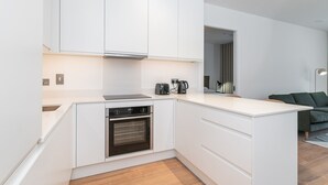 A modern kitchen with white cabinetry, a built-in oven, and a coffee maker. - The Lookout by Dublin At Home (Dublin)