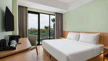 Habitación de hotel con cama, escritorio, silla, televisión y balcón con vistas.