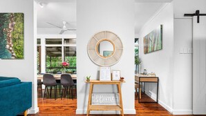 A modern living room with a teal sofa, a wooden coffee table, and a wall-mounted mirror. - Zen City Tropics Fenced Yard - Balcony - Desk (Darwin)