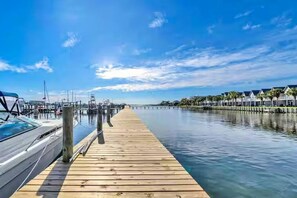 A wooden dock extending into calm water, with a marina and buildings in the background. - Pirates Bay A208 – Bayfront Studio with Water Views! (Fort Walton Beach)