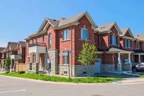 A suburban neighborhood with brick houses, a clear sky, and a street sign reading "MOONSEED LANE". - Modern House Steps From Dining, Shopping & Lakes (Aurora)