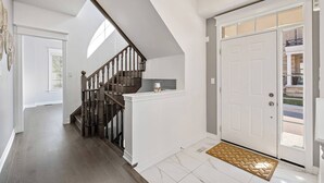 Ein modernes Interieur mit Treppe, einer weißen Tür und Fußmatte.