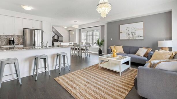 Eine moderne Küche mit einer zentralen Kochinsel, grauen Sofas und einer Kronleuchter.
