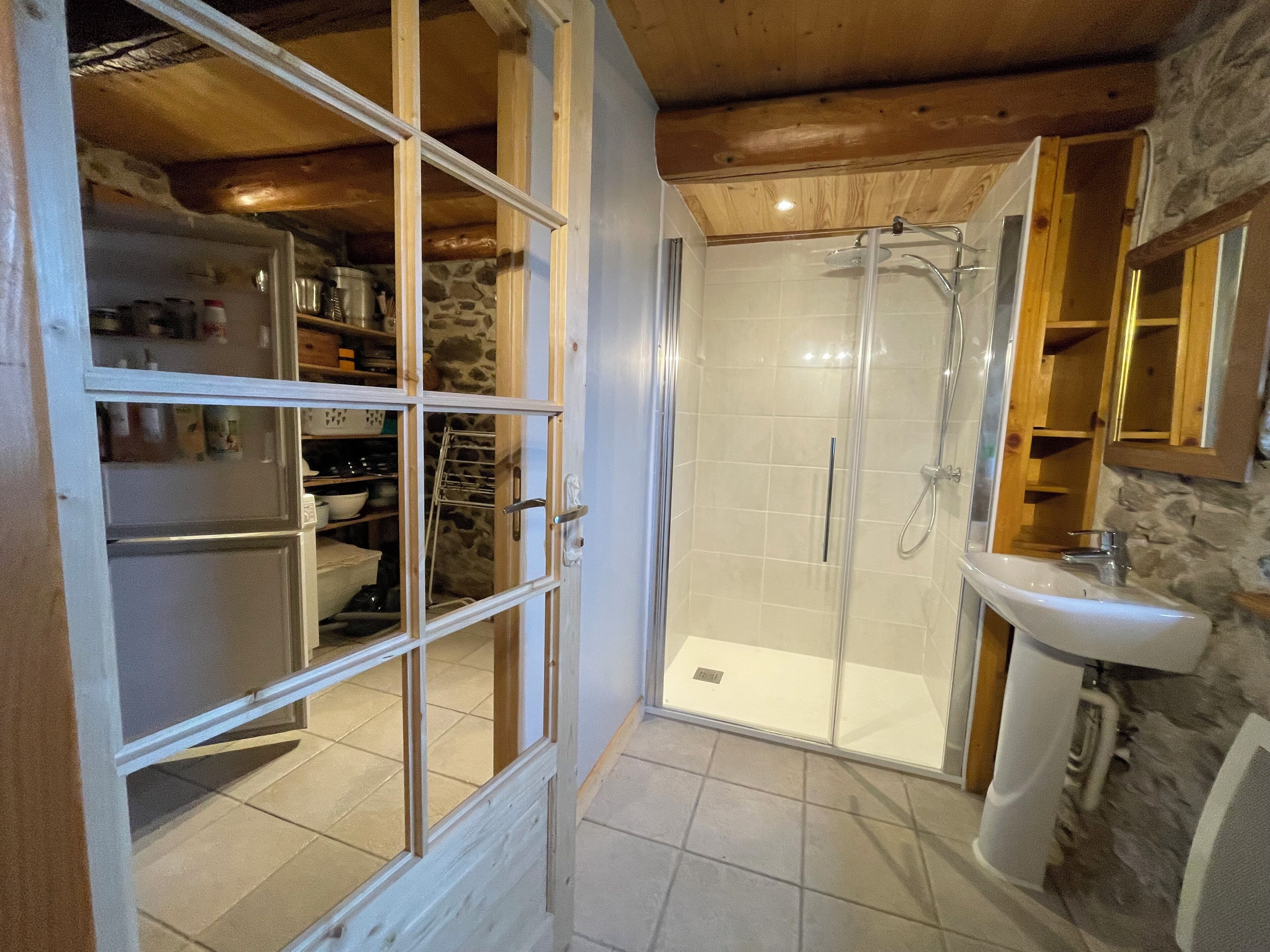 Un baño con ducha, lavamanos y un armario de almacenamiento.