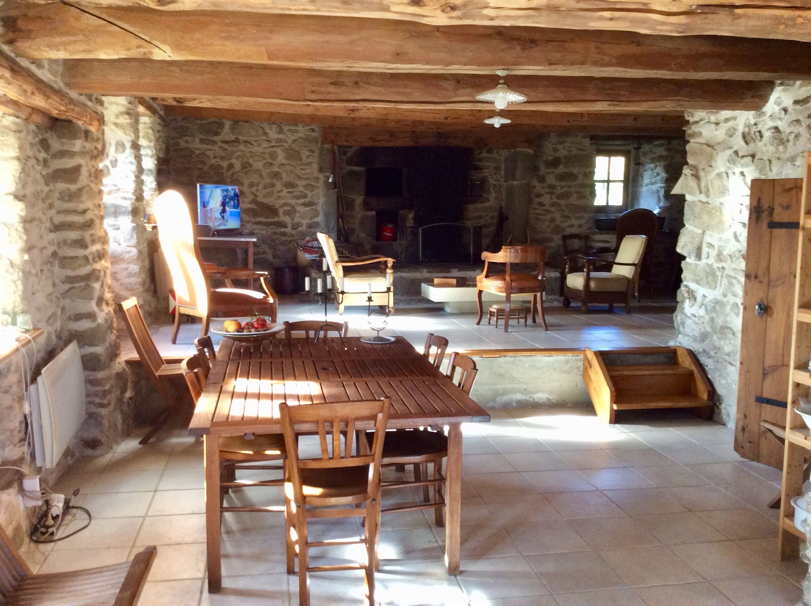 Un interior rústico con una mesa de comedor de madera, paredes de piedra y una chimenea.