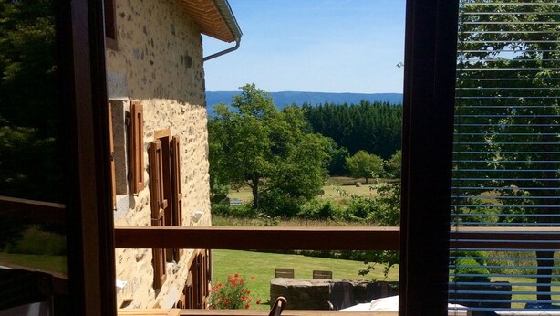 Una terraza de madera con vistas a un edificio de piedra y un paisaje cubierto de césped.