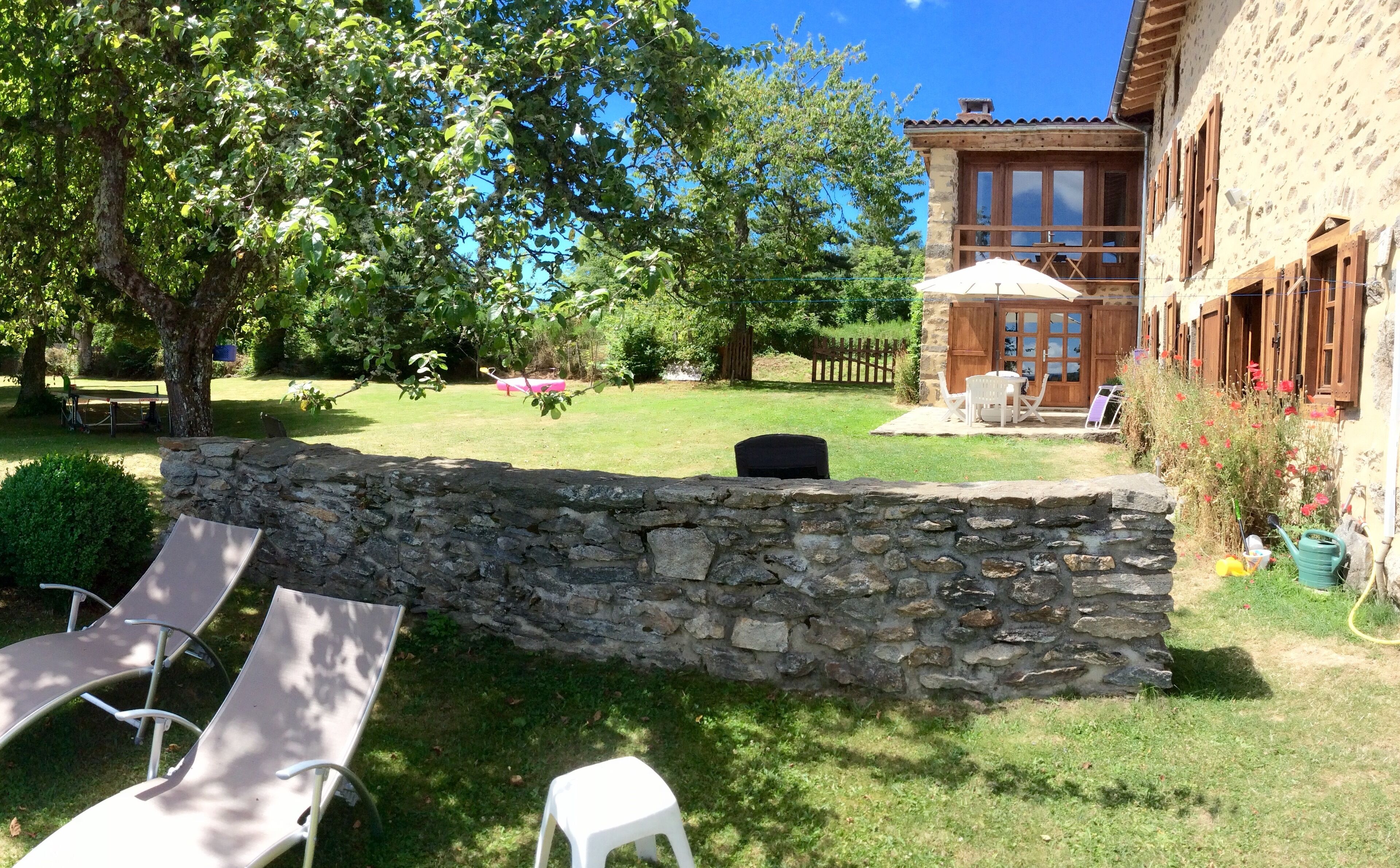 Un muro de piedra, un patio con césped y un edificio con balcón.