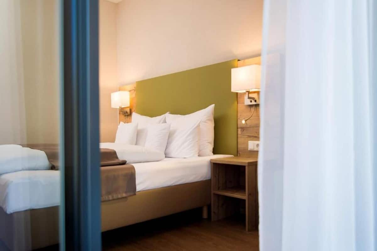 Una habitación de hotel con una cama, una mesita de noche y una lámpara.
