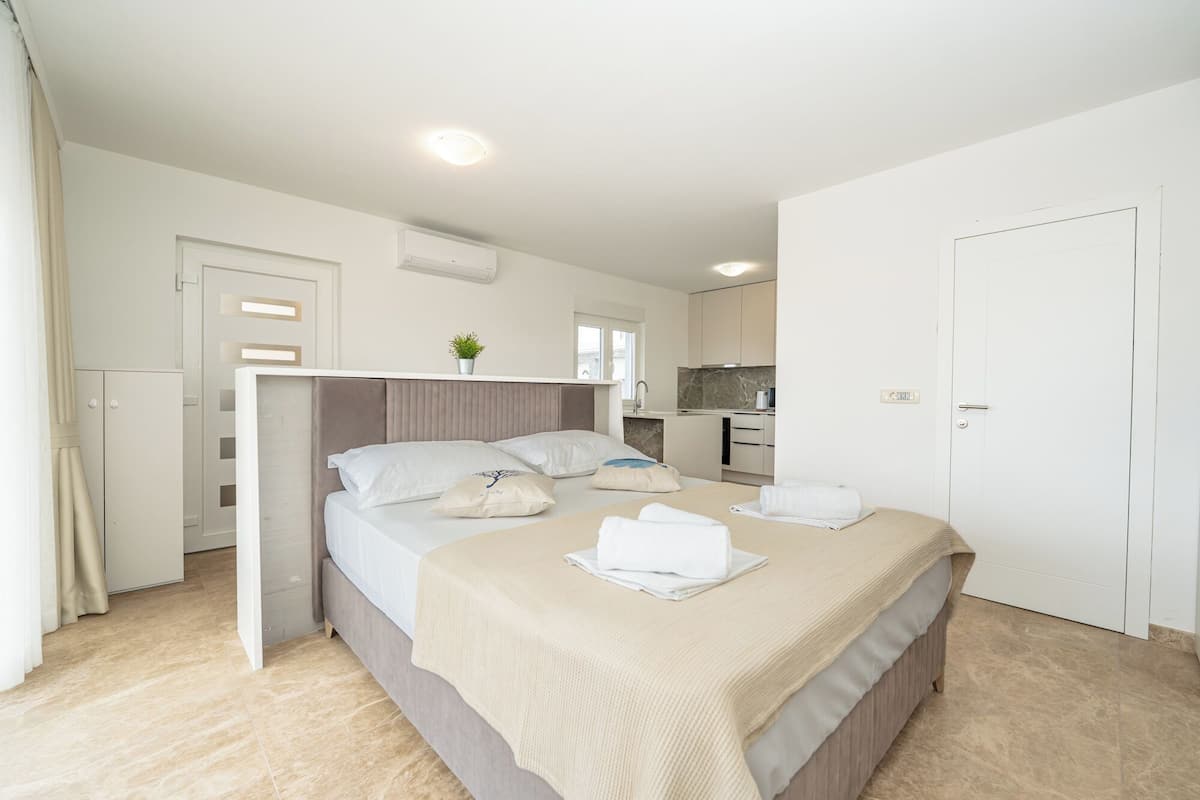 Una habitación de hotel moderna con cama, mesitas de noche, una pequeña cocina y baño.