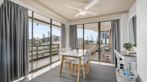 A modern living room with a dining area, large windows, and a view of the city. - Fountain Court 24 - Walk to Everything! The Ultimate Coastal Escape in the Heart of It All! (Port Macquarie)