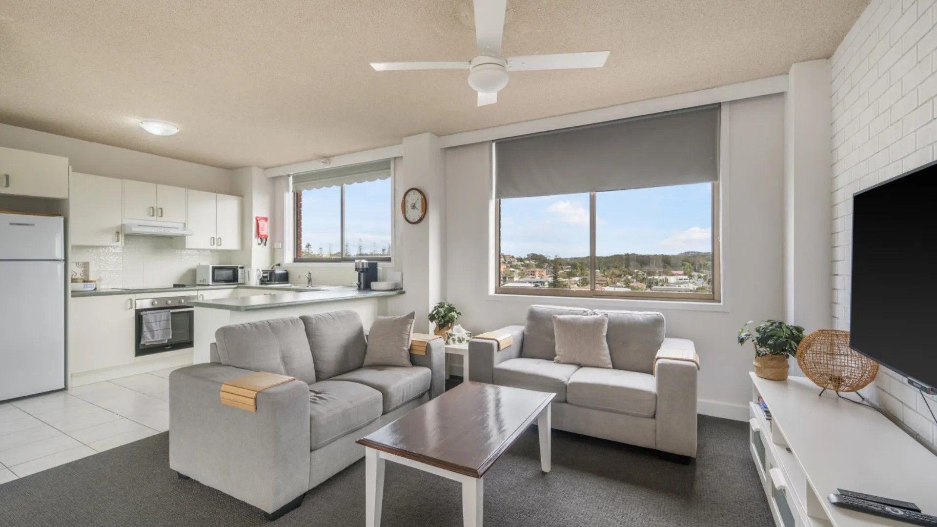 A modern living room with a sofa set, a coffee table, a TV, and a view of the city.