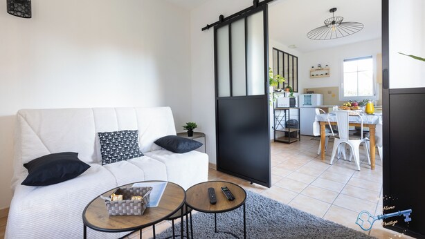 En moderne stue med sofa, sofabord og en skydedør, der fører til et køkken.