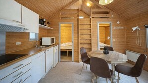 Une cuisine de style cabane, compacte et en bois, avec un coin repas, un four à micro-ondes intégré et une échelle menant à une chambre en mezzanine.