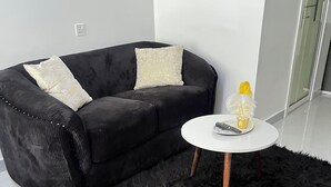 A modern living room with a black sofa, two decorative pillows, a white coffee table, and a fluffy rug. - Modern studio close to JKIA and SGR Syokimau (Nairobi)