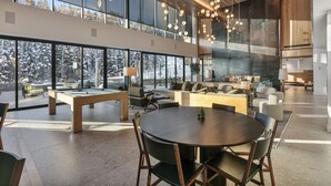 A spacious living area with a pool table, comfortable seating, and large windows offering a view of the outdoors. - Ski-in/out Deer Valley Resort Pool 3br 3 Bedroom Condo (Park City)