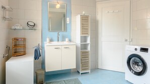 A bathroom with a sink, mirror, towel rack, and a washing machine. - Apartment Le 47: Spacious Holiday Home with Wi-Fi in Alsace (Thann)