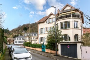 A residential street with houses, parked cars, and a gated driveway.