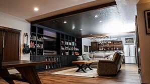 Een gezellige woonkamer met een houten salontafel, een bank en een boekenkast vol boeken en decoratieve spullen.