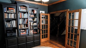 Een bibliotheek met donker houten boekenkasten, een open haard en een trap naar een hoger niveau.