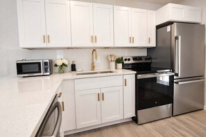 A modern kitchen with white cabinets, stainless steel appliances, and a stainless steel refrigerator. - Bay Esplanade By GoldenCoastRentals (Clearwater)